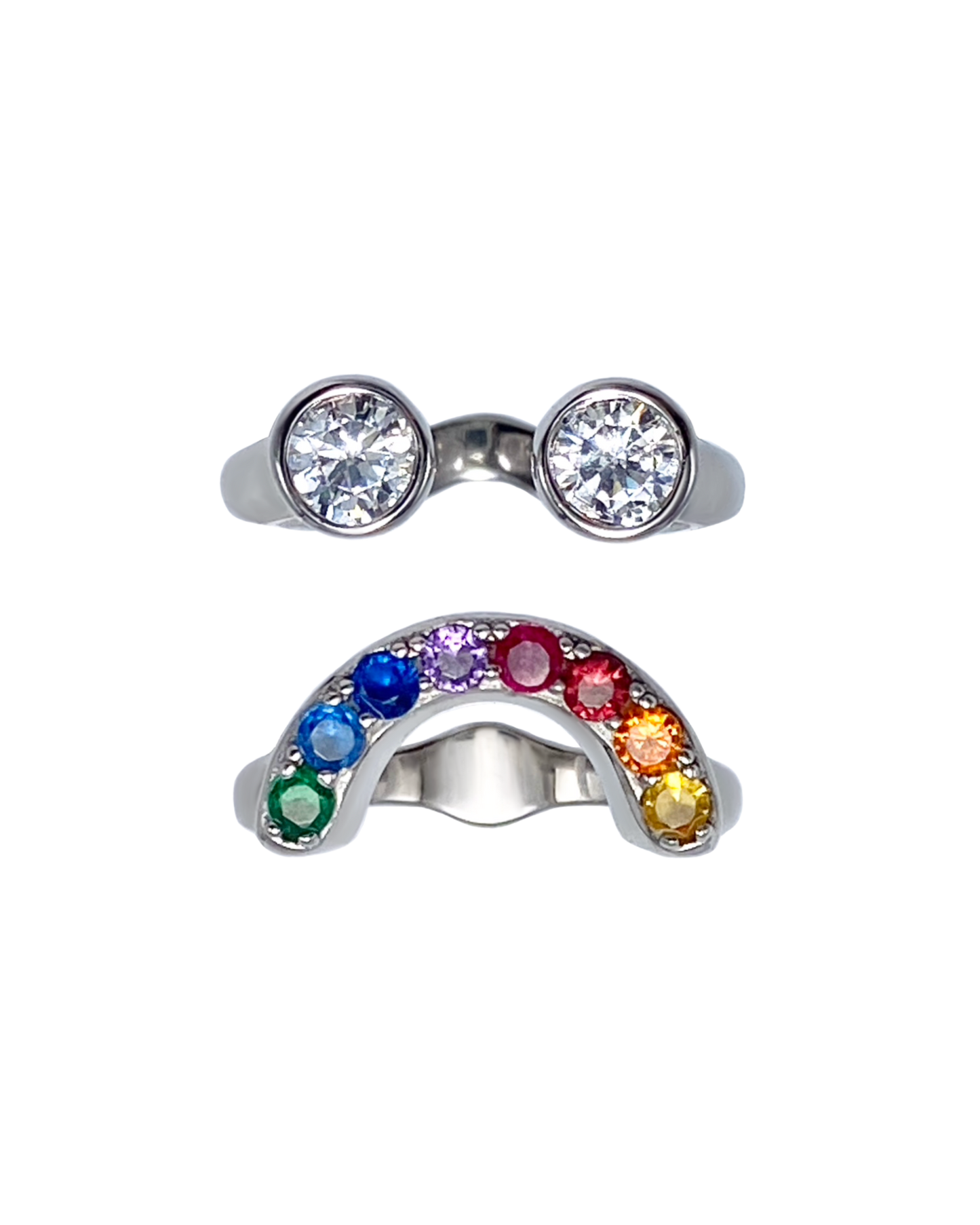 Silver ring with two zircon gemstones and another arch shaped ring with rainbow-colored gemstones that together make a sad looking smiley face