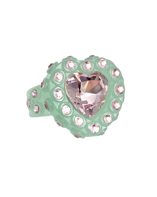 Ring with heart-shaped pink gem and green band on a white background