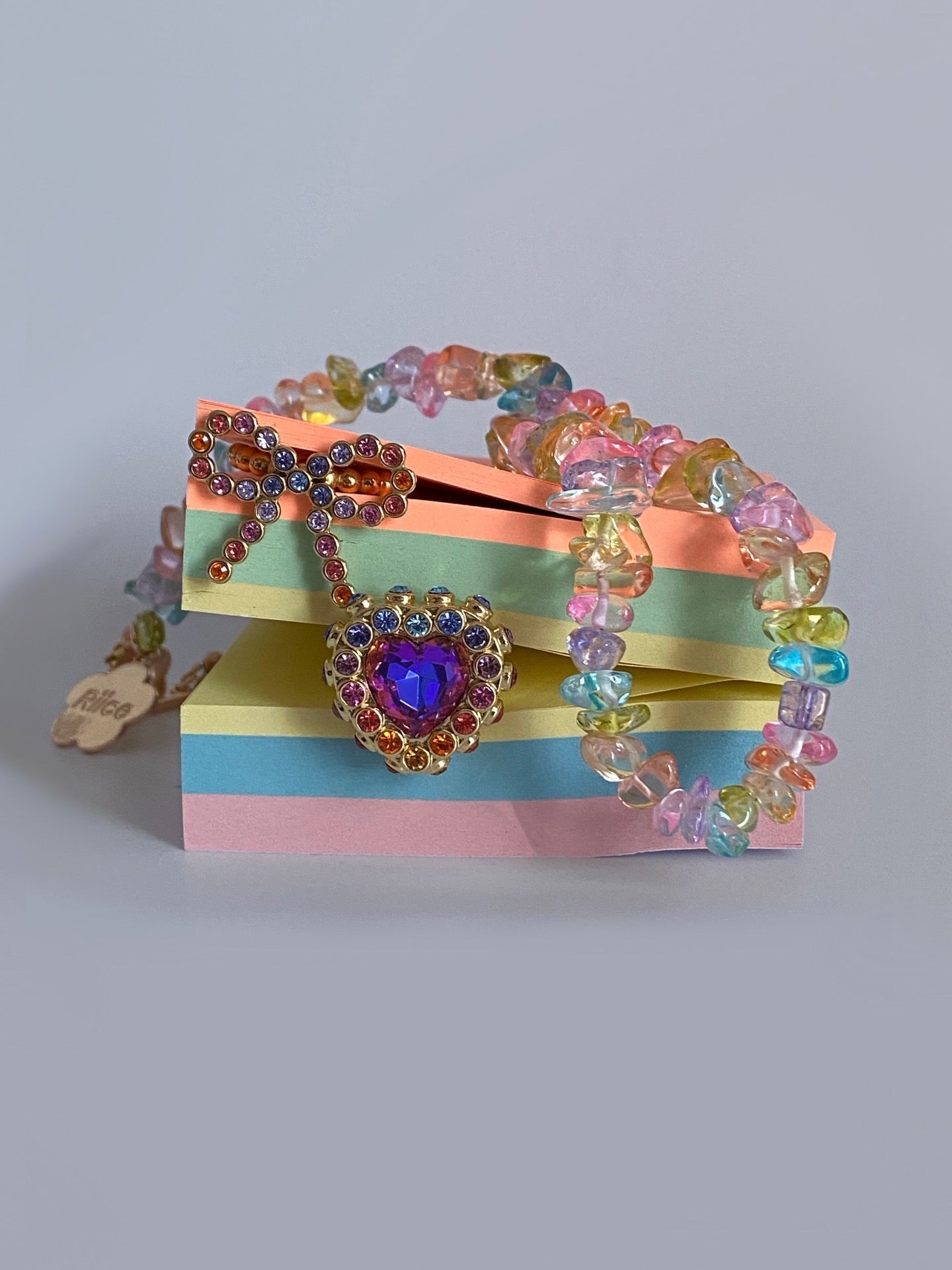 Colorful beaded bracelet with a heart-shaped clasp on a striped box against a gray background