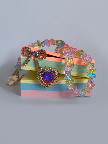 Colorful beaded bracelet with a heart-shaped clasp on a striped box against a gray background