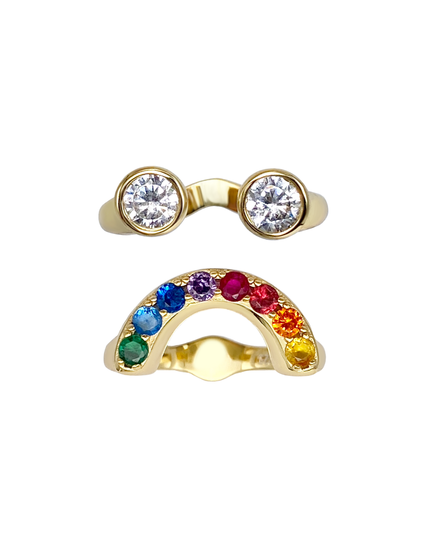 Gold ring with two large round zircons and an arch shaped ring with colorful gemstones that together form a sad looking smiley face