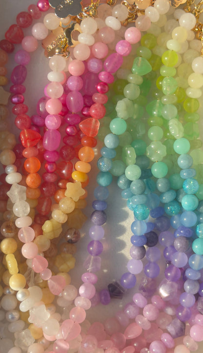Colorful beaded necklaces arranged in a rainbow pattern.