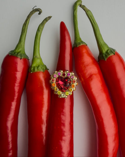 Red chili peppers with a colorful heart-shaped ring on a gray background