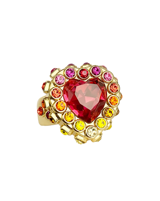 Gold ring with a heart-shaped pink gemstone and smaller colored gems in orange, yellow, red and pink gradient