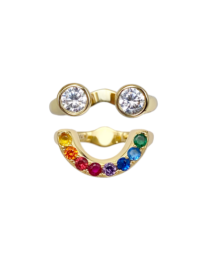 Gold ring with two circular gemstones and a rainbow-colored gemstone band that together form a smiley face ring set.