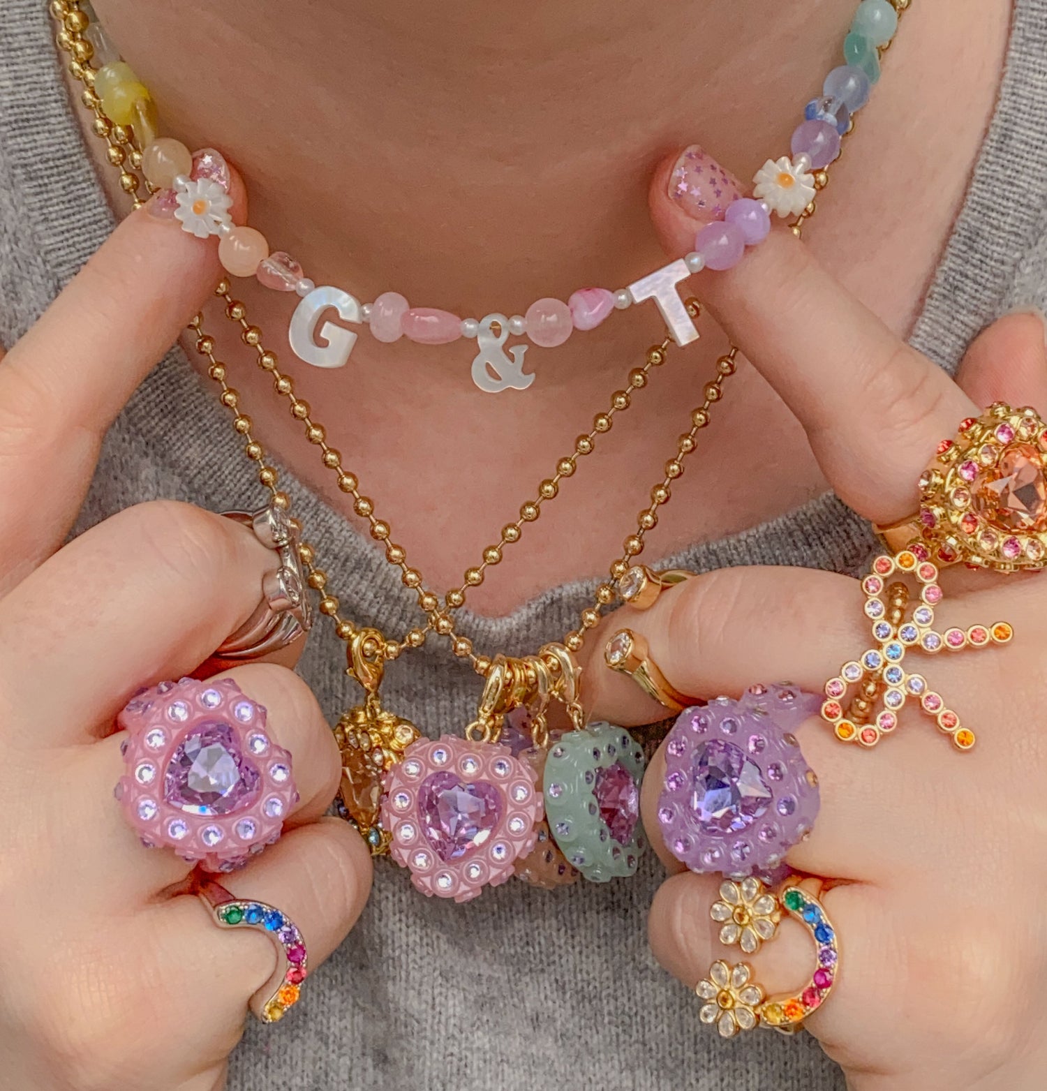 Close-up of hands wearing colorful jewelry including necklaces and rings.
